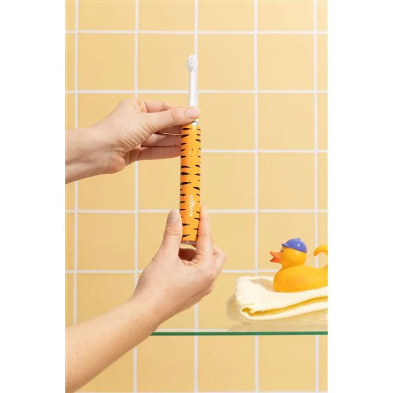 Mains tenant la brosse à dents sonique MyVariations Kids Tigre près d'un lavabo de salle de bain ave