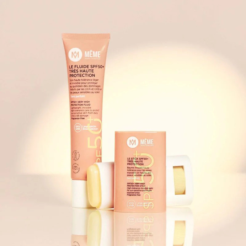 Tube de fluide MÊME SPF50+ présenté avec stick solaire assorti sur surface ambient avec éclairage do
