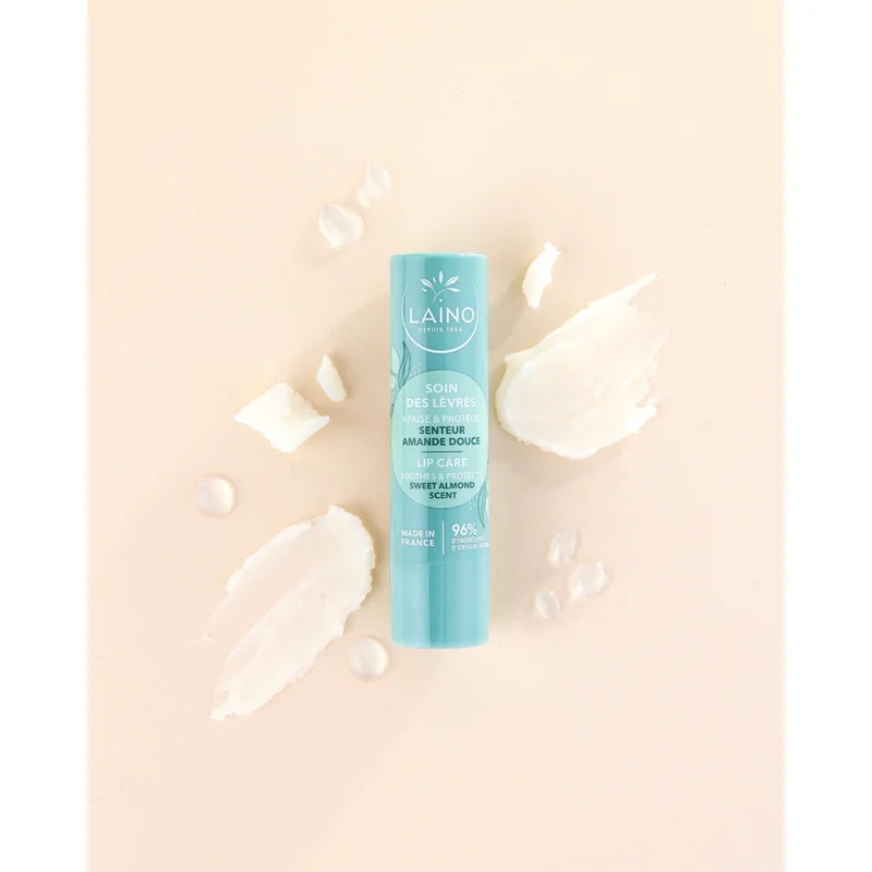 Tube de baume à lèvres Laino entouré d'éléments à l'huile d'argan : fruits, feuilles, échantillons d