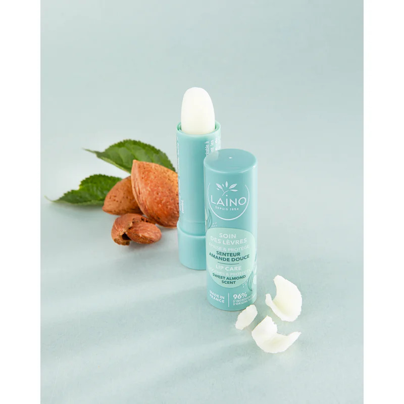 Texture crémeuse blanche du baume avec morceaux et swatches à côté du stick Laino Amande Douce sur f