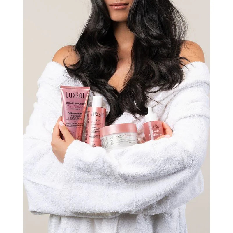 Vue de côté de la bouteille rose Luxéol L’Huile Brillance sur fond blanc, mettant en valeur le pipet