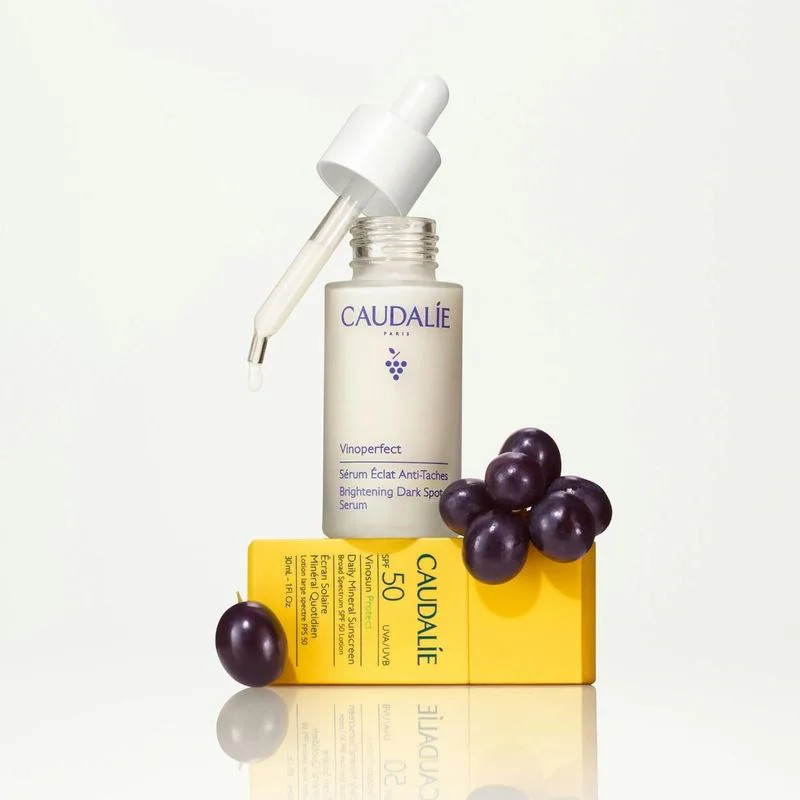 Vue rapprochée ambient du duo Caudalie 1112431 avec pipette de sérum ouverte gouttant l'essence, tub