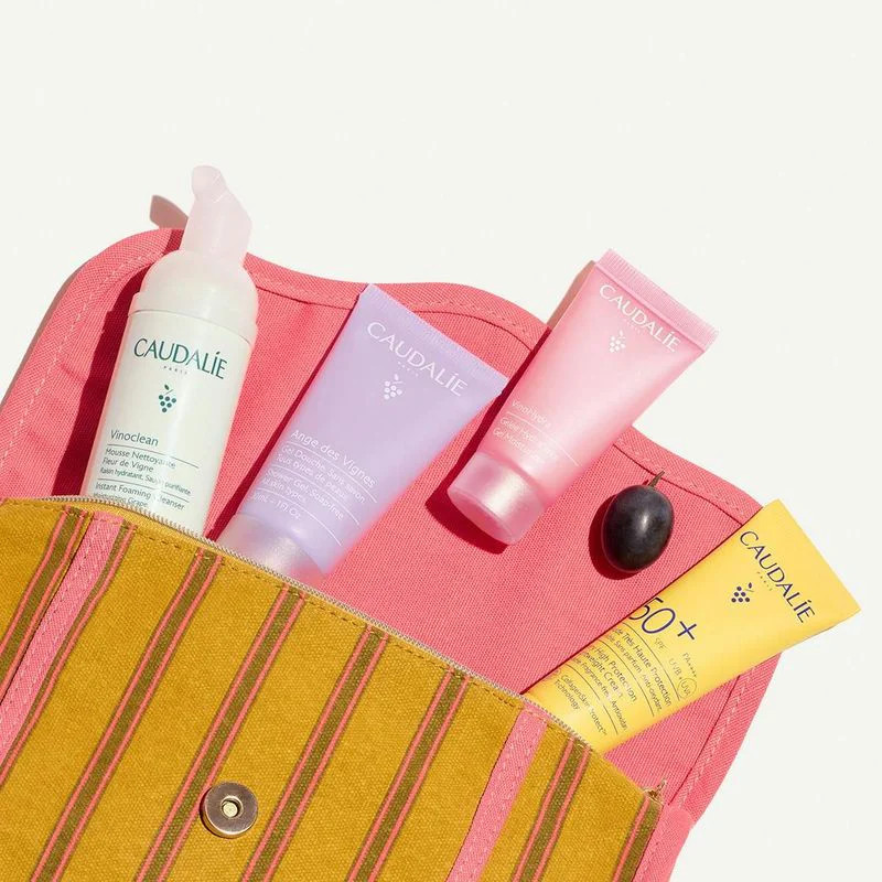 Gros plan sur le bord de la trousse d'été Caudalie, mettant en valeur la bordure rose, les rayures j
